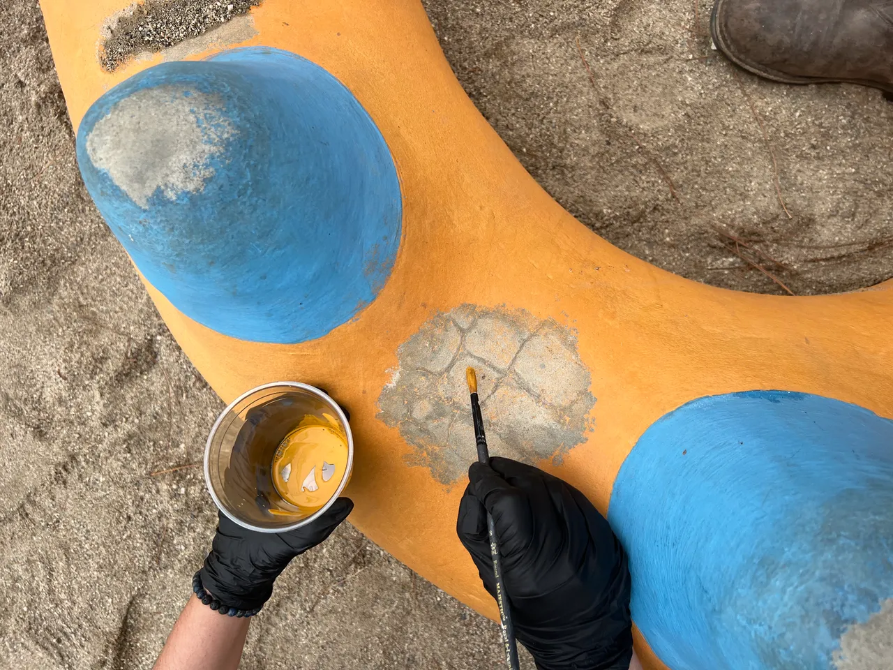 Jennifer painting fine colorful details on a concrete dragon sculpture