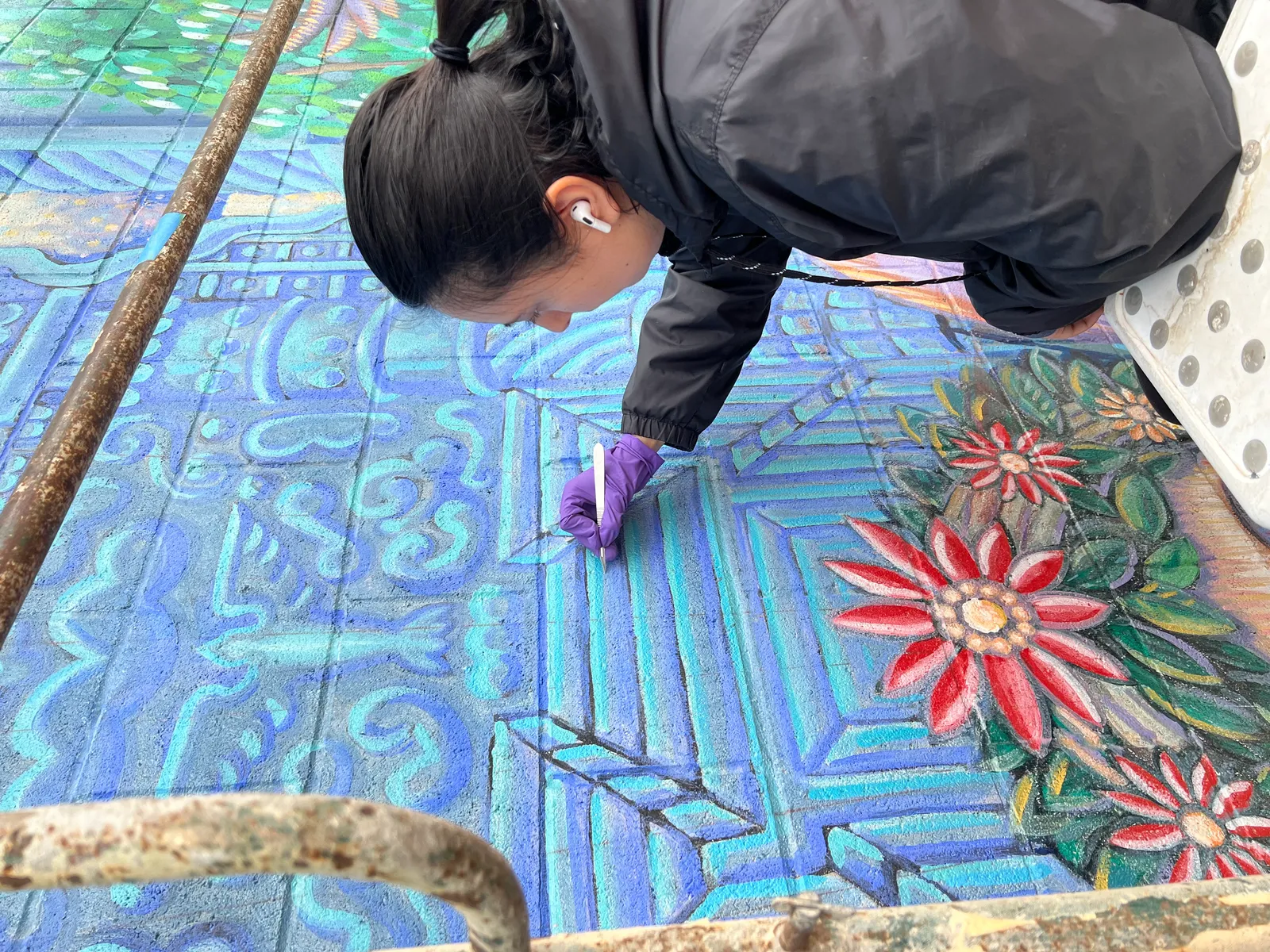Jennifer removing surface dirt from the mural using conservation sponges
